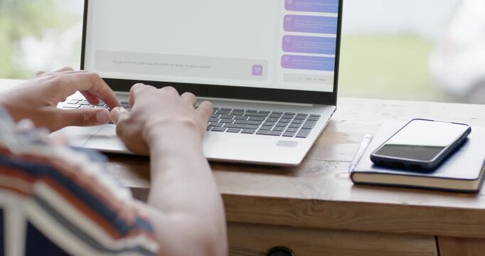 Hands are typing on laptop keyboard at wooden desk by window, prompted by messages