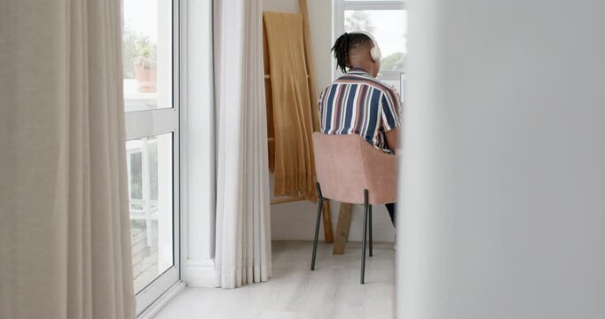 Camera revealing seated person gesturing at laptop during online call near glass door