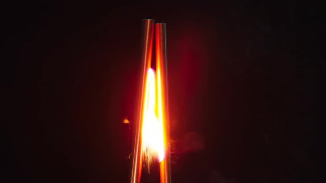 Bright electric arc discharging between two metal rods on dark background