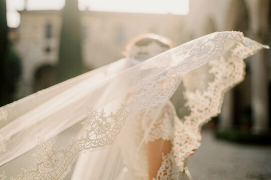 Windblown bridal veil close up with elegant lace details at outdoor wedding venue
