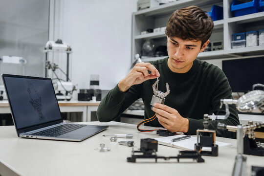 Robotics Engineering Student Testing Gripper Prototype on Workbench