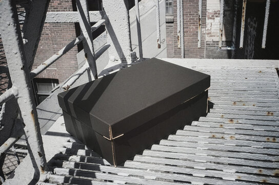 Black postal box packaging mockup template on outdoor metal stairs