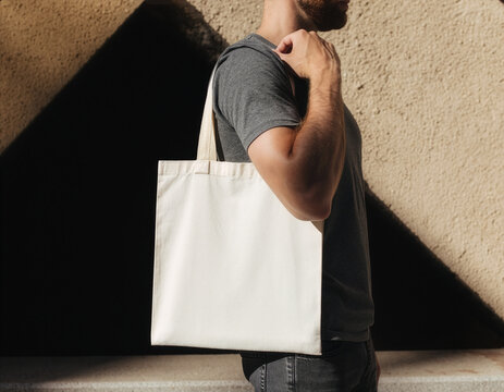 White canvas tote bag mockup template worn by person against concrete wall