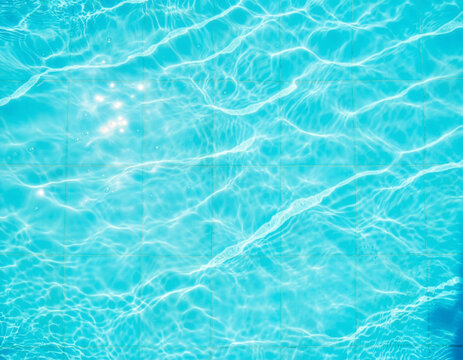 Crystal blue pool water texture background template with sunlight ripples