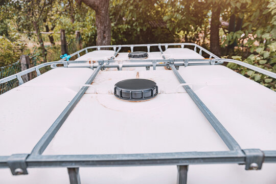 Close-up of plastic IBC tote tank lids and metal cage frame outdoors, used for bulk liquid storage and water collection. Agriculture concept.