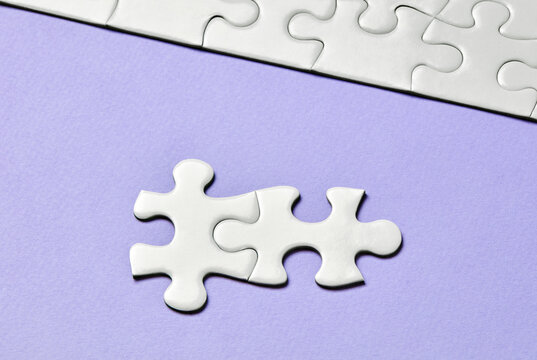 Two interlocking puzzle pieces on purple background