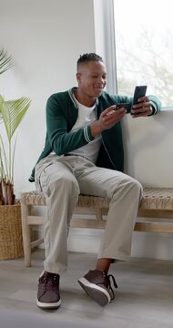 Vertical video: Man holding 2 phones comparing screens by window to pick main phone