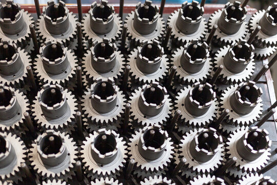 Close-up of gear components on storage rack in tractor manufacturing factory. Heavy machinery production, automotive supply chains, technical reliability in heavy industry.