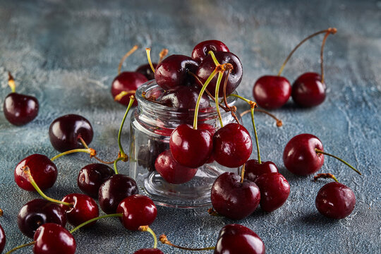 Fresh Cherry or sweet cherry with water drops lying on a background with a blue tint.