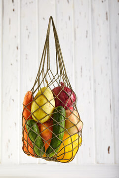 Mesh shopping bag with organic eco vegetables on white background with copy space. Caring for the environment and the rejection of plastic concept. Zero waste shopping concept. Sustainable lifestyle