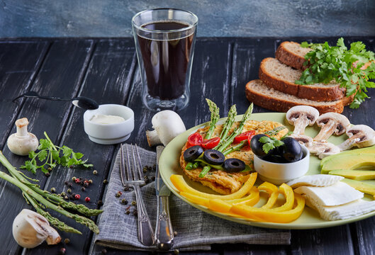 Healthy Diet Breakfast vegetables on a plate - scrambled eggs, avocado, bell pepper, sherry tomatoes, olives, fresh mushrooms, esparagus, greens, tfatit cheese and a glass of espresso coffee.