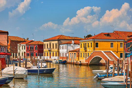 Island Murano in Venice Italy. View on canal with boats and motorboats on water. Summer day picturesque landscape.