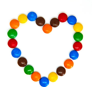 Colorful chocolate buttons in the shape of heart on a white background