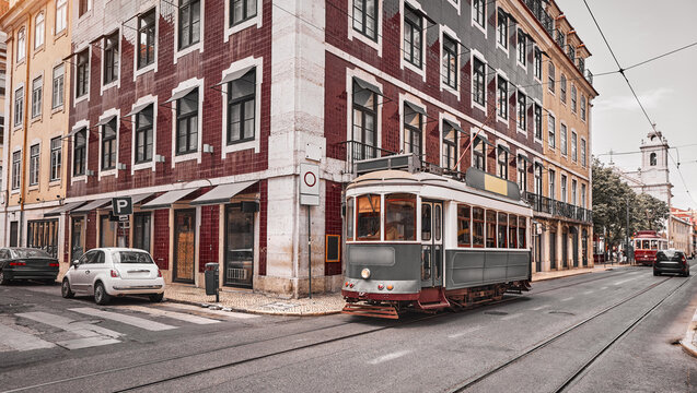 Lisbon, Portugal. Old retro tram riding by tramlines at street of old town. Traditional house with decorative tile azulejo on background.