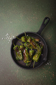 Padron peppers fried cast iron skillet sea salt dark green background Spanish appetizer top view