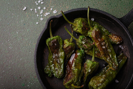 Padron peppers fried cast iron skillet sea salt dark green background Spanish appetizer top view