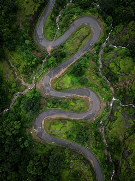 Vertical aerial shot of a zig zag mountain pass road surrounded by lush green tropical jungle with mountain tropical landscape