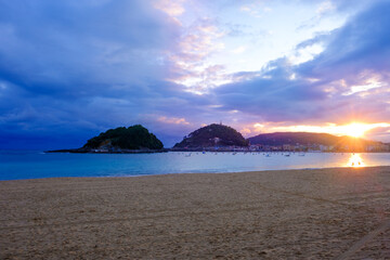 Fototapeta premium Sunrise in La Concha Bay, San Sebastian Donostia, Basque Country, Spain. Scenic view of Urgull mountain and city skyline.