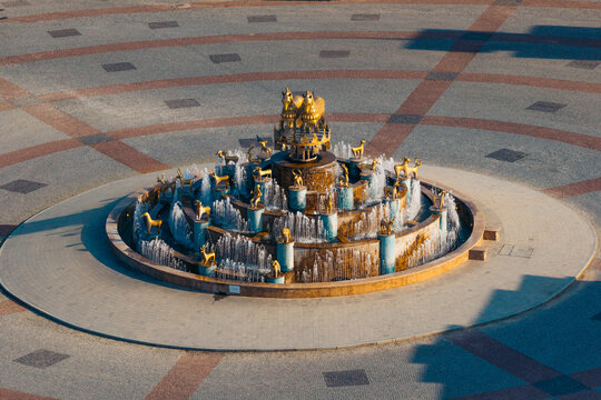 Aerial view of the Colchis Fountain with its golden animal statues and tiered water jets in the center of a paved square in Kutaisi, Imereti, Georgia.