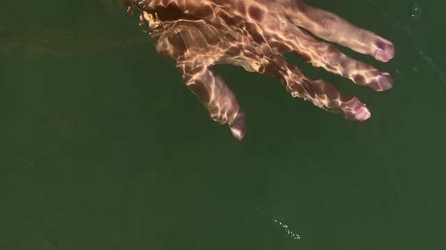 Woman touching seawater with hand. 4k