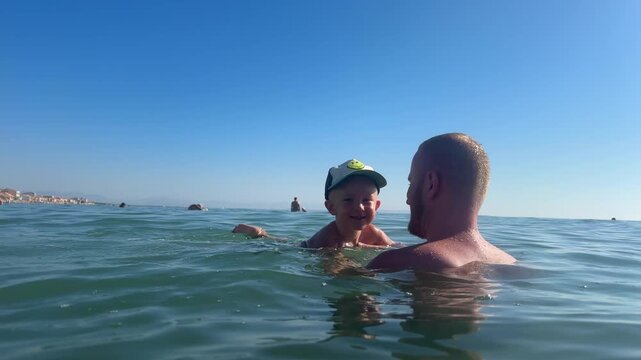 Father playing with son in the sea. 4k