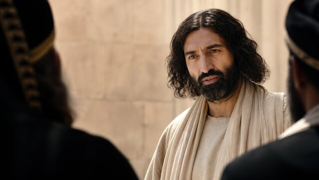 Man with beard in biblical robe answering question of religious leaders in temple courtyard. Confrontation about authority and faith. Gospel teaching and parable concept