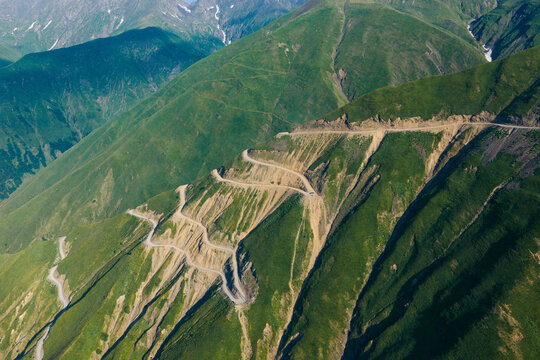 Aerial view of the winding Abano Pass mountain road carved into steep green slopes with dramatic switchbacks in Akhmeta Municipality, Kakheti, Georgia.
