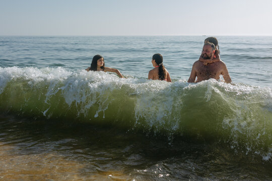 Father and Three Daughters Playing in Ocean Waves