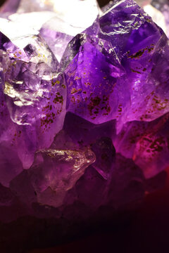 A close-up of a crystalline purple amethyst mineral stone. Selective focus. Macro photography of precious and semi-precious stones. The shiny surface of the precious crystal.