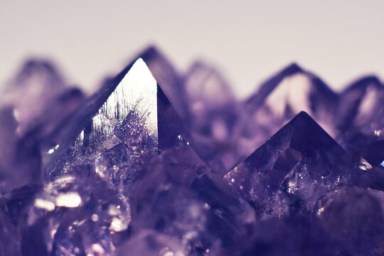 A close-up of a crystalline amethyst mineral stone. Selective focus. Macro photography of precious and semi-precious stones. The shiny surface of the precious crystal.