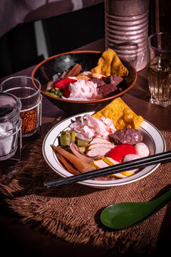 Yentafo pink noodle soup served with crispy wontons, fish balls, and condiments on a rustic wooden table, reflecting authentic Thai and Asian street food culture. 