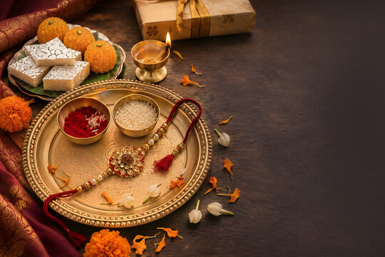 Raksha Bandhan Celebration with Traditional Rakhi, Indian Sweets, Kumkum, Rice and Diya on Festive Brass Thali