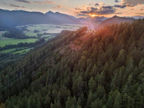 Aerial view of mountains over Svarin on Cierny Vah valley with a high-voltage power line crossing dense pine forest during sunset in Kralova Lehota, Zilinsky kraj, Slovakia.