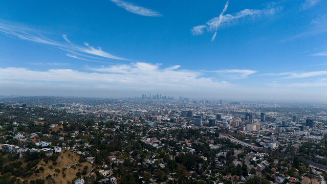 Aerial view of the Hollywood Reservoir and the sprawling cityscape of Los Angeles under a bright blue sky with wispy clouds, Los Angeles, California, United States.