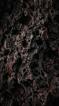 Close up detail of dark porous volcanic rock texture.