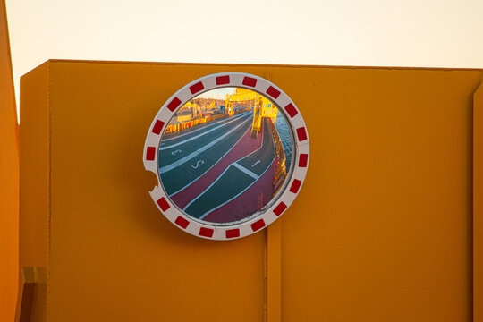 Convex mirror reflecting empty ferry lanes in warm evening light.