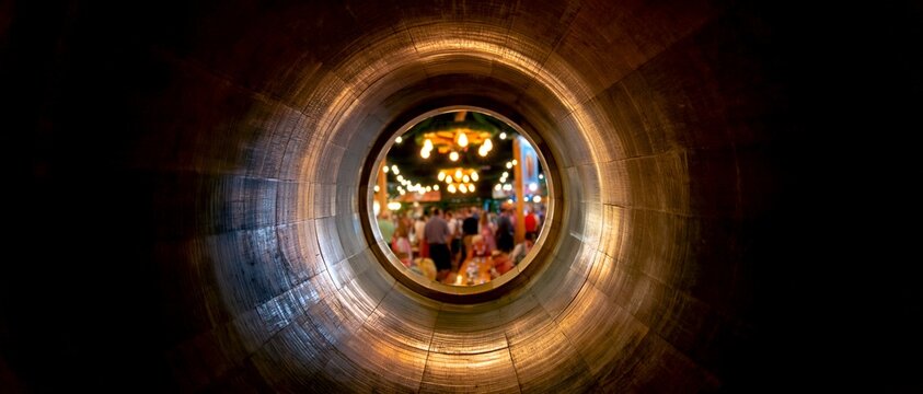 View through tunnel opens to lively, glowing crowd partying