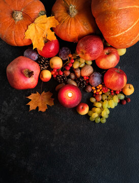 burning candle, fruits, pumpkins, nuts, autumnal leaves on dark background. Witchcraft, esoteric spiritual ritual for fall season, Mabon Holiday. symbol of Harvest, Thanksgiving. top view. copy space