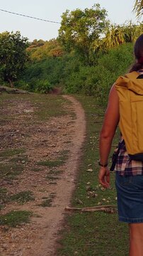 Vertical video. Female Traveler Walking Near Grazing Cow on Nusa Penida Along Remote Island Trail, Rural Adventure and Nature Exploration