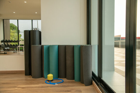 Rolled fitness yoga mats standing in corner of gym fitness studio