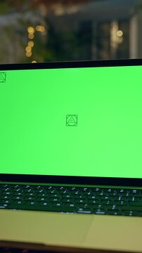 Vertical video. Laptop With Green Screen Mockup on Outdoor Table Near Pool in Tropical Resort at Night, Remote Work and Digital Communication
