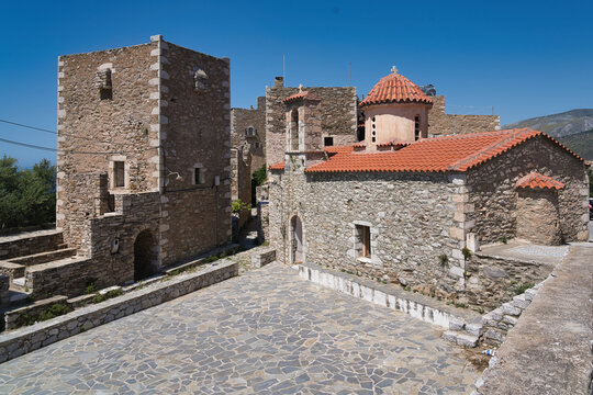 Fortified stone tower houses and a small Byzantine church with red tiled roof in the historic village of Vathia.