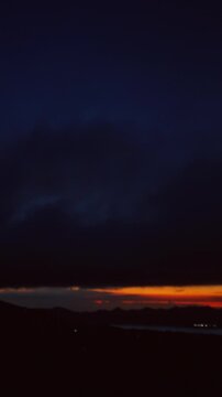 Vertical video. Timelapse Sunrise Over Gunung Batur With Fast Moving Clouds Above Dark Volcanic Silhouette and Glowing Horizon Revealing Mountain Wilderness