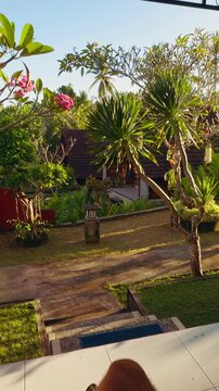 Vertical video. First Person View From Resort Terrace Over Tropical Garden And Villas During Sunny Afternoon, Leisure And Vacation Lifestyle
