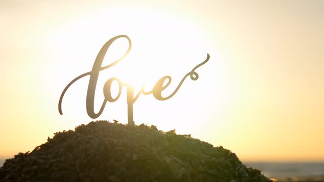 Black outlines word Love at dawn sunset on sky on seashore. Stick contours in shape word Love in sand on background of setting, rising sun on seashore. Concept Love infatuation Valentine's Day holiday