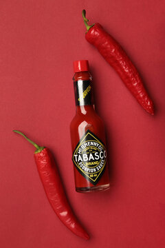 Mykolaiv, Ukraine - August 19, 2026: A bottle of Tabasco pepper sauce with red chili pepper on red background. Vertical photo