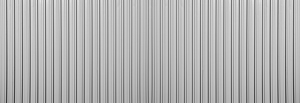 Silver tin iron corrugated wall with horizontal stripes from a metal profile of a metal sheet. Texture, background. grey wall fence texture for backdrop galvanized gray facade.