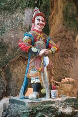 An ancient-style painted stone guardian deity statue stands on the entrance steps of Huyen Khong Cave in the Marble Mountains of Da Nang. © RayBreen
