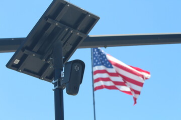 Flock camera monitoring a parking lot as an american flag waves in the background.  © Sebastian