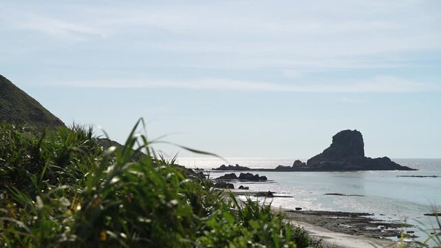 Dramatic coastal view of 'Yahe-iwa', a towering megalithic sea rock on Iheya Island, Okinawa. Shot from the beach at sunset.